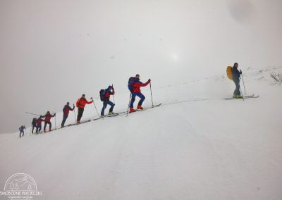 Zima, grupa narciarzy idzie gęsiego